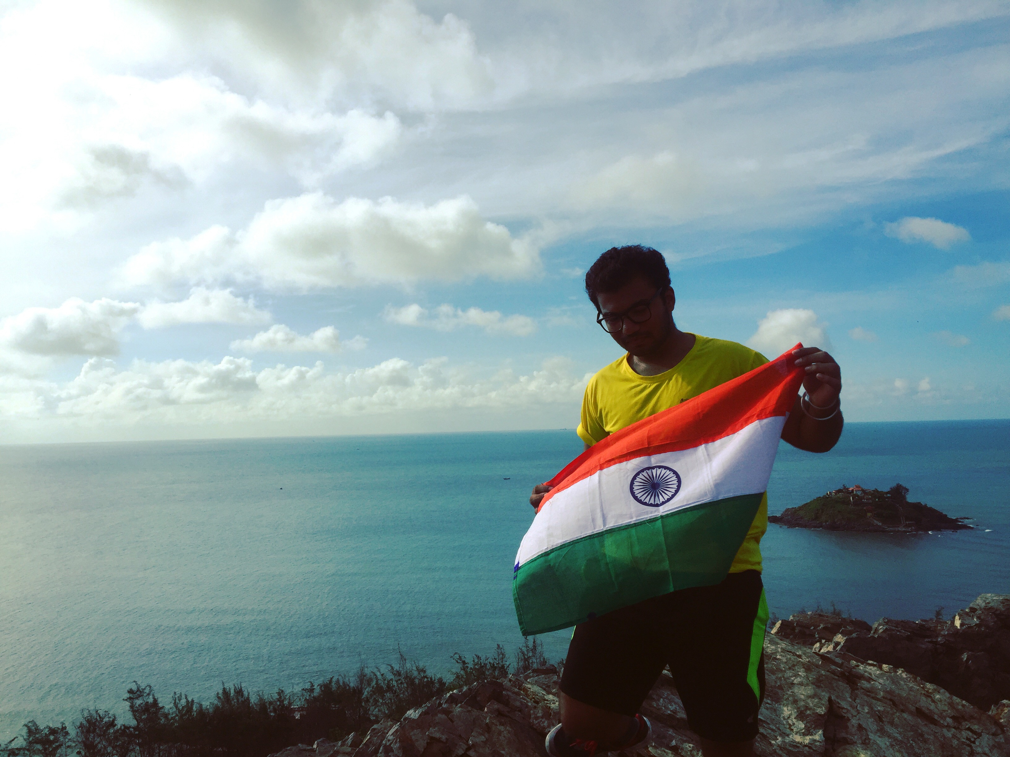 Indian guy holding indian flag in front of the sea