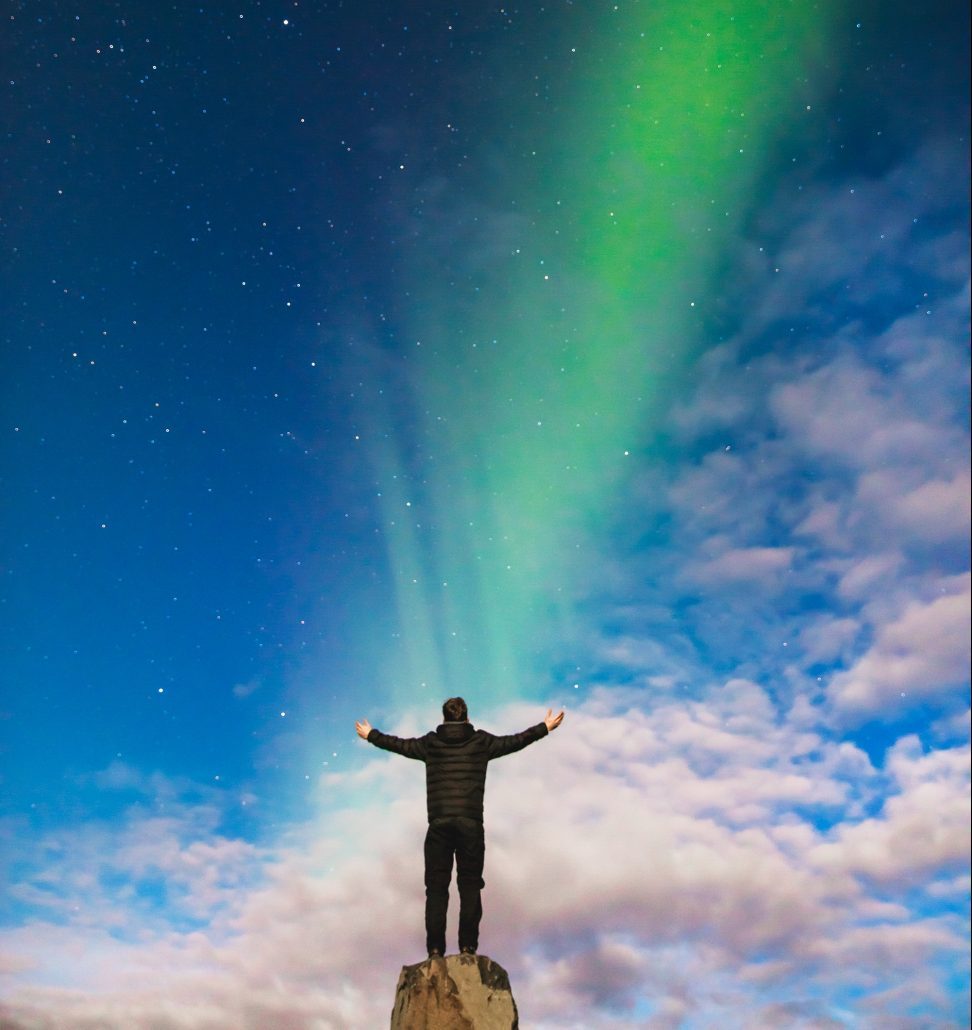 men standing in front of the northern lights - climate change